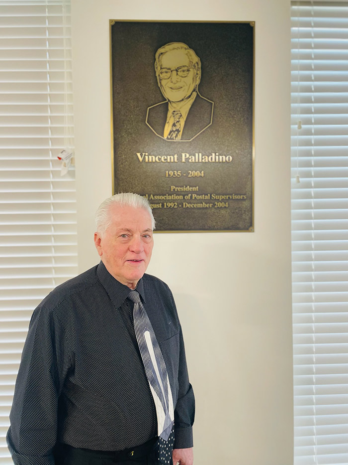 Tommy under plaque of President, Vincent Palladino